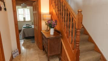 Staircase leads to an upper floor, featuring a console table with a vase and a sign that reads 'A DAY AT THE BEACH RESTORES THE SOUL'.