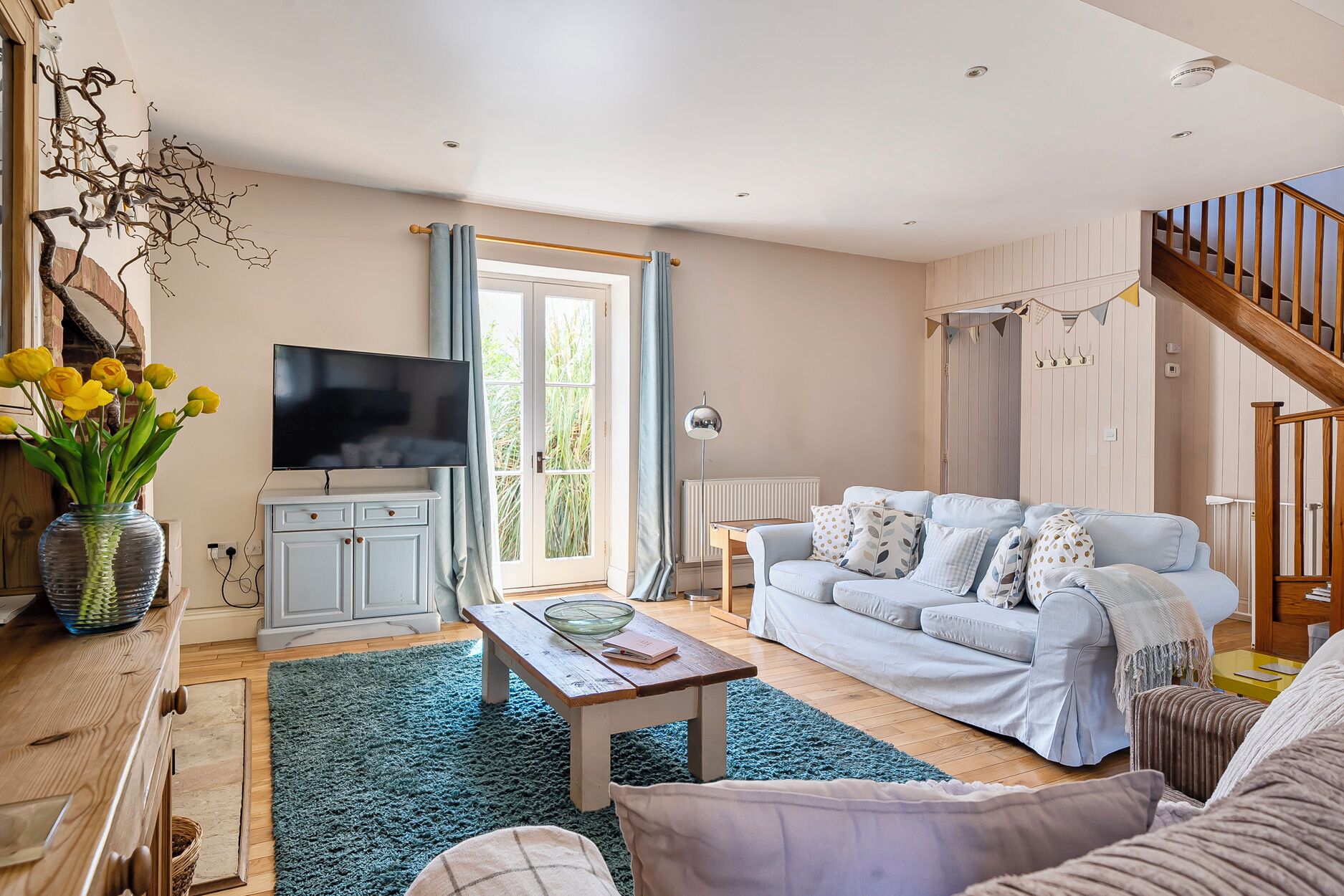 Ein Wohnzimmer mit Fernseher, Sofa, Couchtisch und einer Treppe.