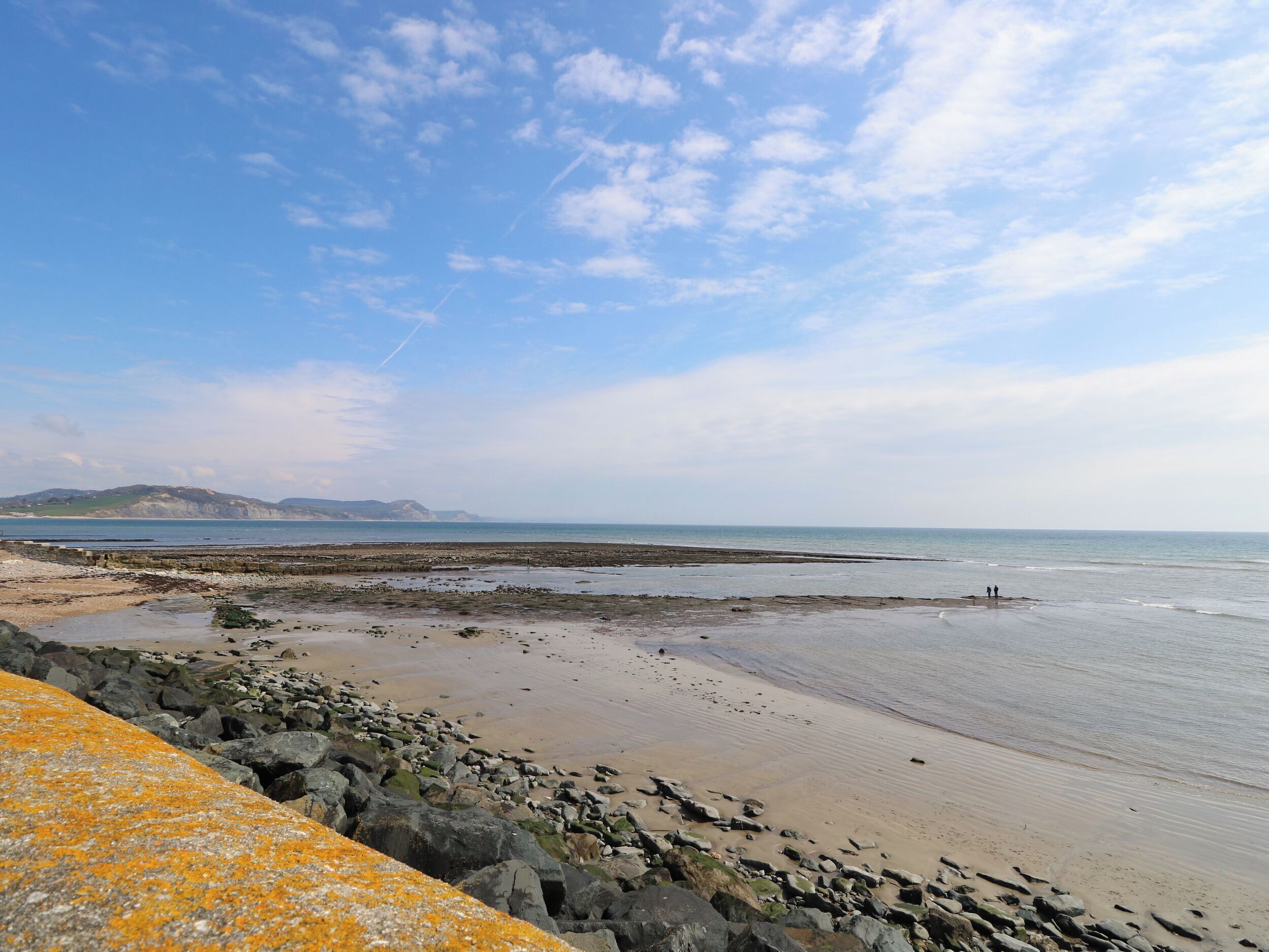 A coastal beach scene with rocky terrain and a clear sky.