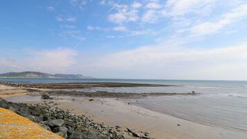 A coastal beach scene with rocky terrain and a clear sky.