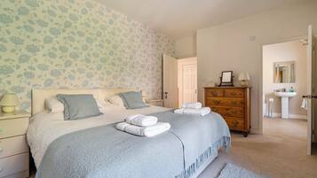 A bedroom with a bed, dresser, nightstand, and a bathroom visible through an open door.