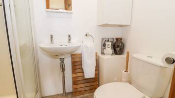 Ein kleines Badezimmer mit einem weißen Waschbecken, einer Toilette und einer Dusche.