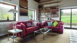 Un salón amplio con un sofá rojo, una mesa de centro y una estantería llena de libros.