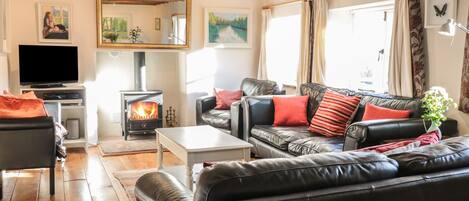 A cozy living room with a fireplace, leather sofa, and a flat-screen TV.