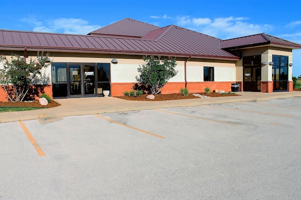 A building with a red roof, beige and red walls, and a parking lot. - Americas Best Value Inn Fredonia (Fredonia)