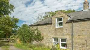 A stone house with a gravel driveway and a wooden gate.