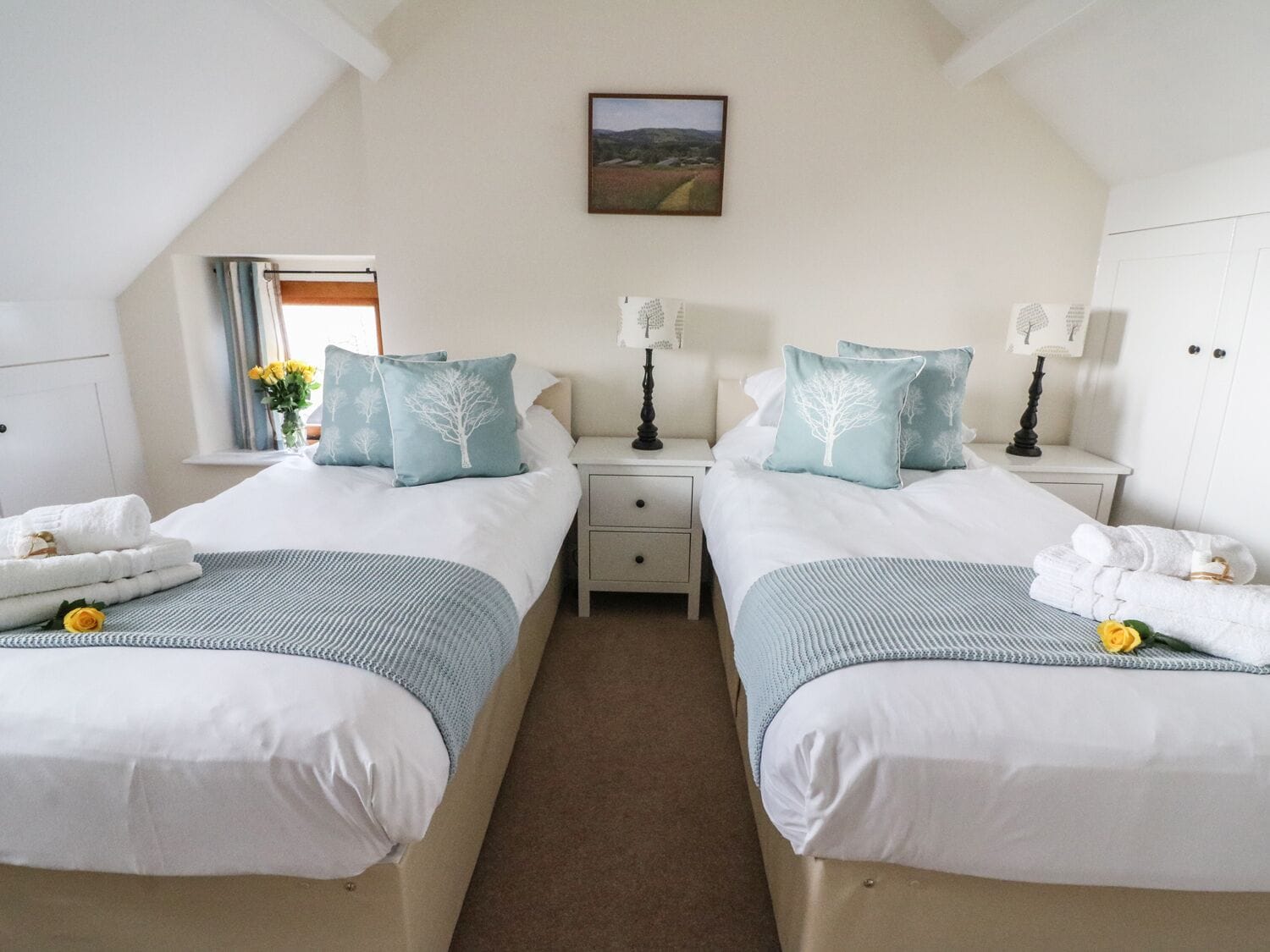 Habitación doble con dos camas, cada una con almohadas a juego y una mesita de noche con lámpara.