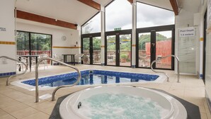 A pool area with a hot tub, a diving board, and a sign indicating a pool depth of 1.4 meters.