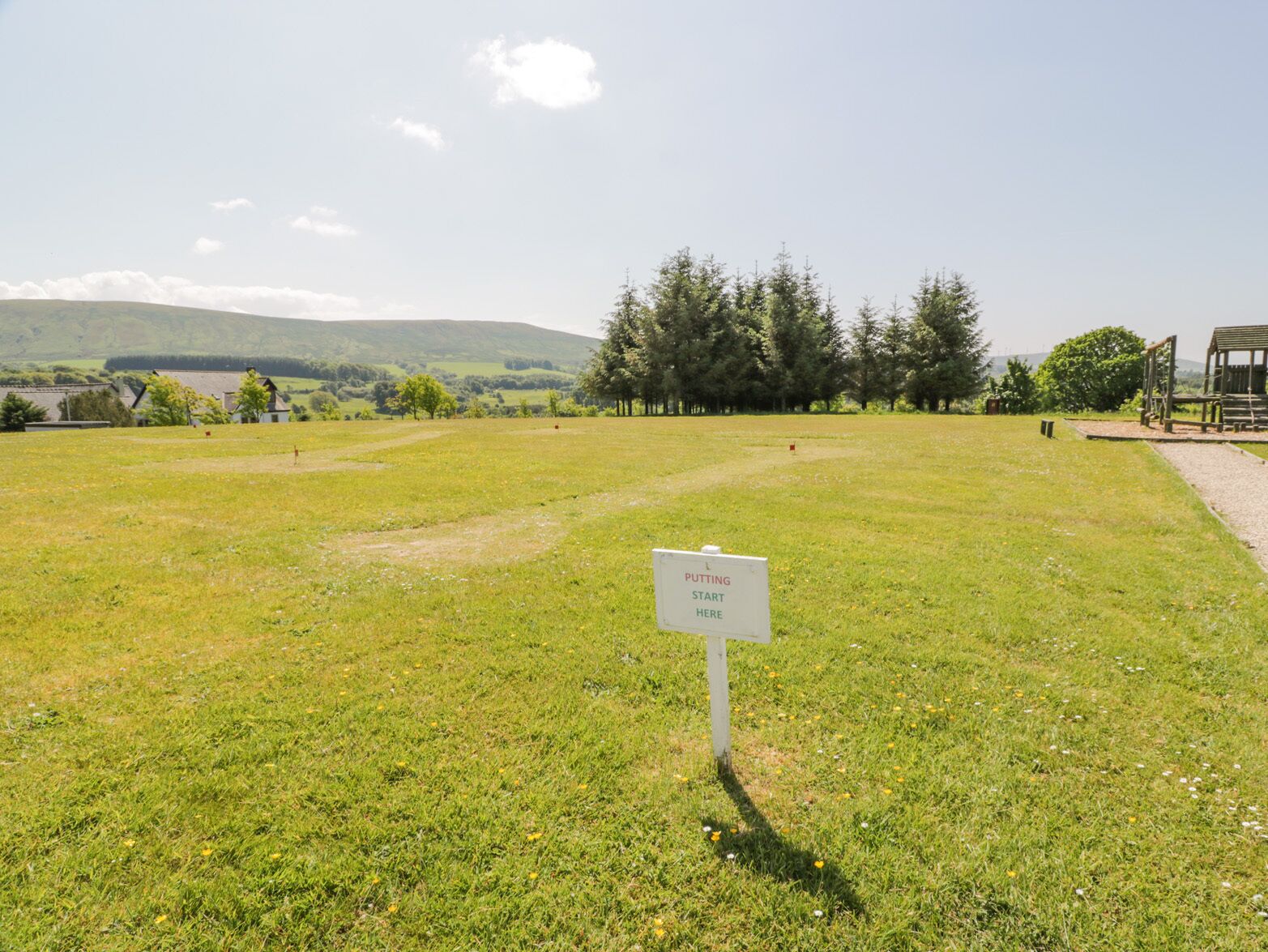 A grassy field with a sign that reads "PUTTING START HERE".