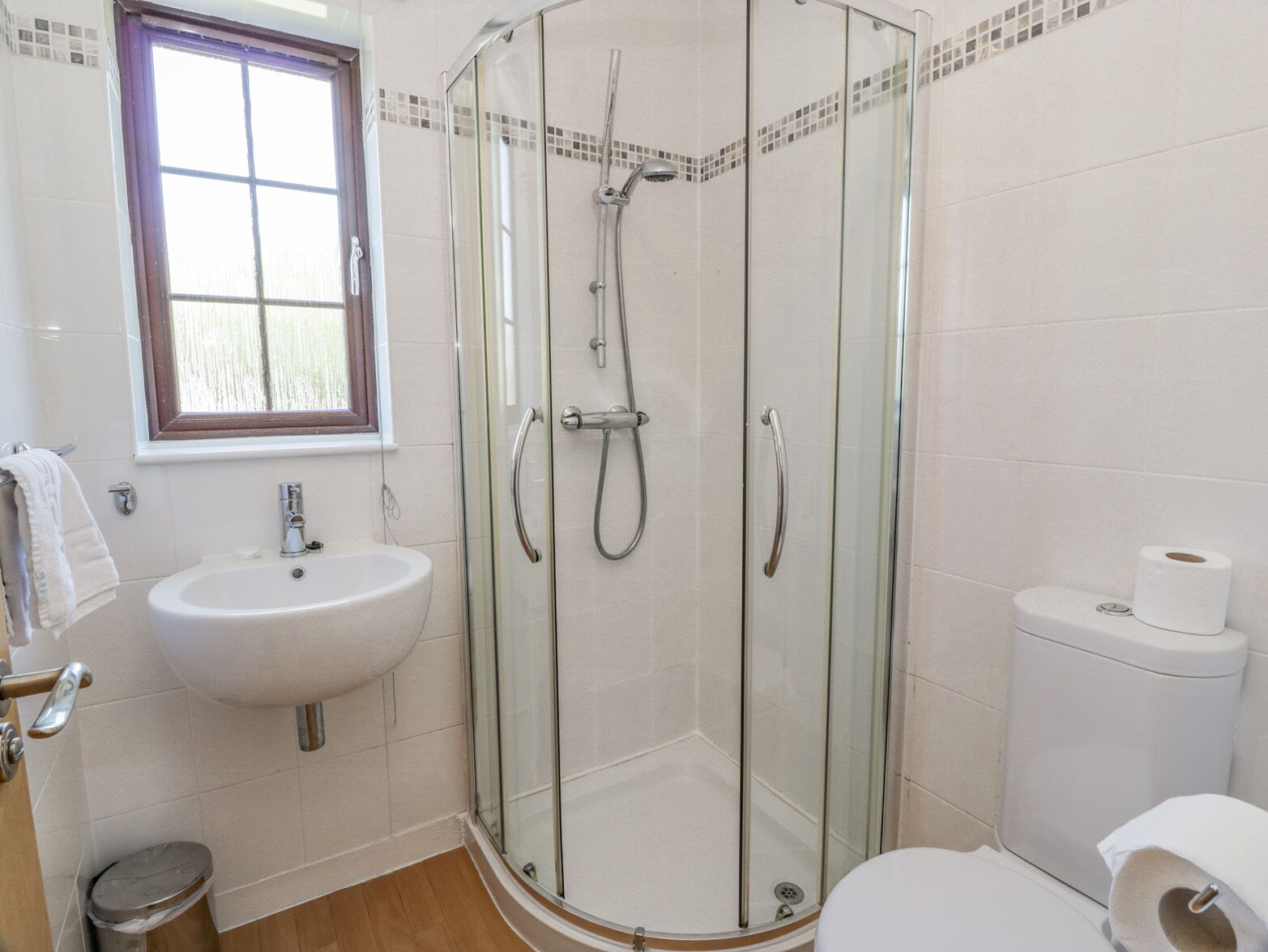 Een moderne badkamer met een douchecabine van glas, een wastafel en een toilet.