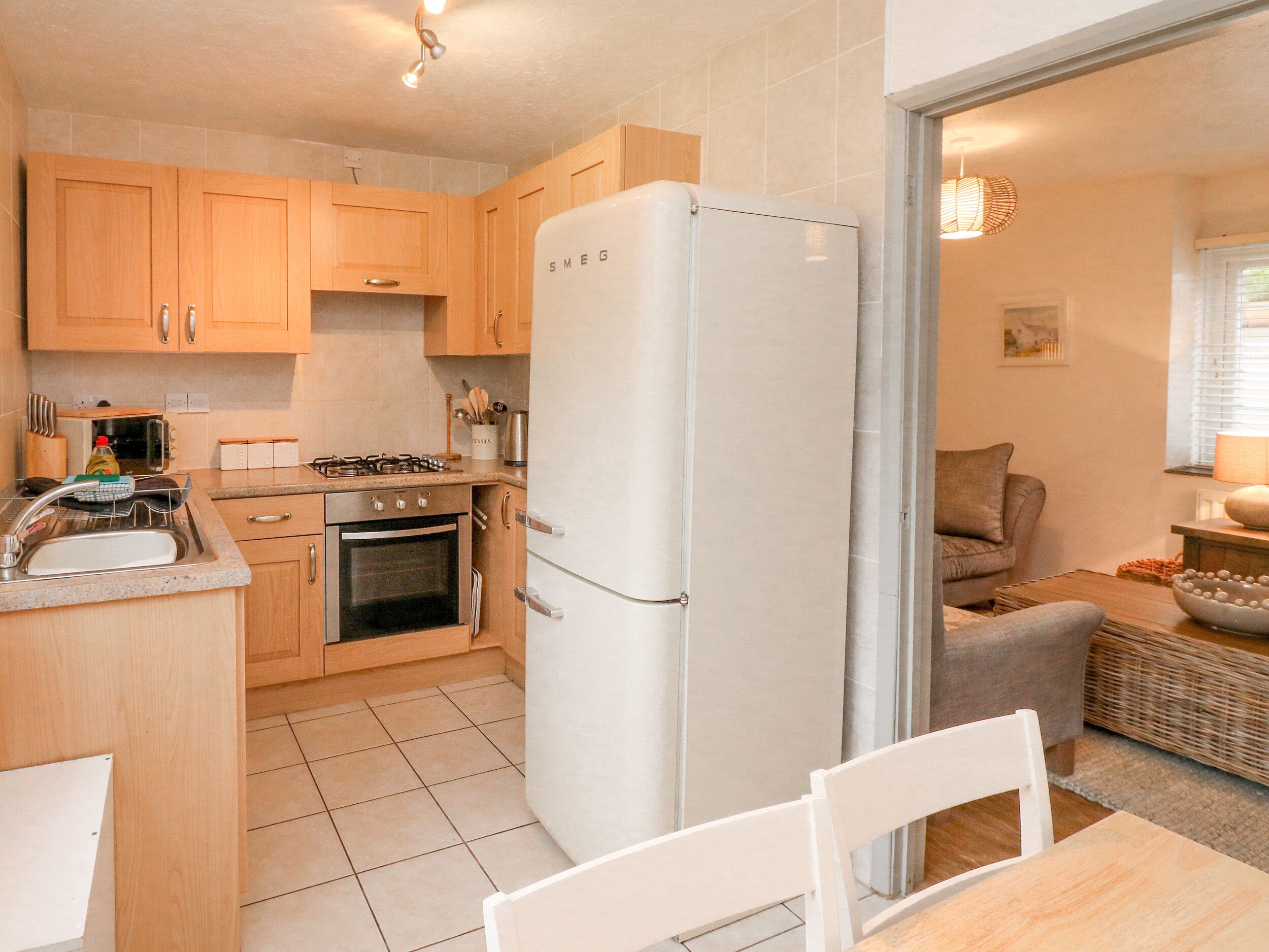 A compact kitchen with wooden cabinets, a white refrigerator, a stove, and a dining area with a table and chairs.