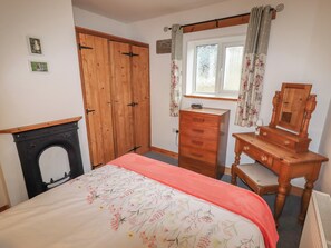 A bedroom with a bed, wooden wardrobe, dresser, and a mirror.