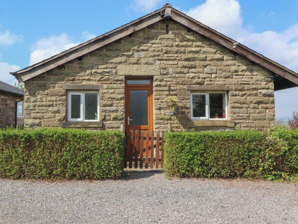 A stone house with a wooden door, two windows, and a gravel driveway.