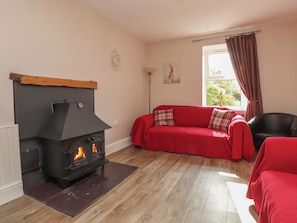 Una sala de estar con chimenea, un sofá rojo y una ventana con cortinas.