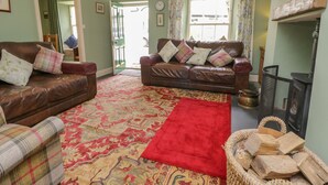A living room with two leather sofas, a red rug, and a fireplace. - Anvil Cottage (Ambleside)
