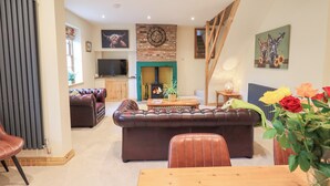 A cozy living room with a fireplace, leather sofas, and a dining table. - Rose Cottage (Carlisle)