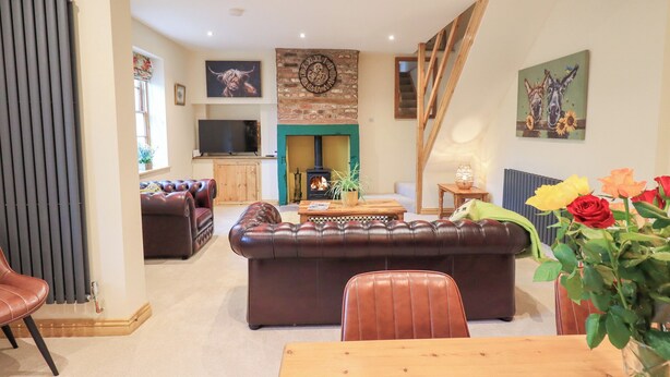 Una sala de estar acogedora con chimenea, sofás de cuero y una mesa de comedor.