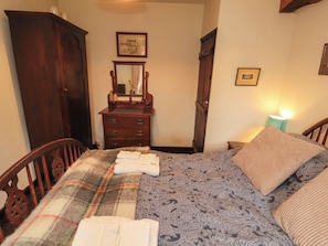 A bedroom with a bed, a dresser, a mirror, and a nightstand with a lamp.