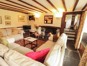A living room with a fireplace, a sofa set, a television, and a stone fireplace surround.