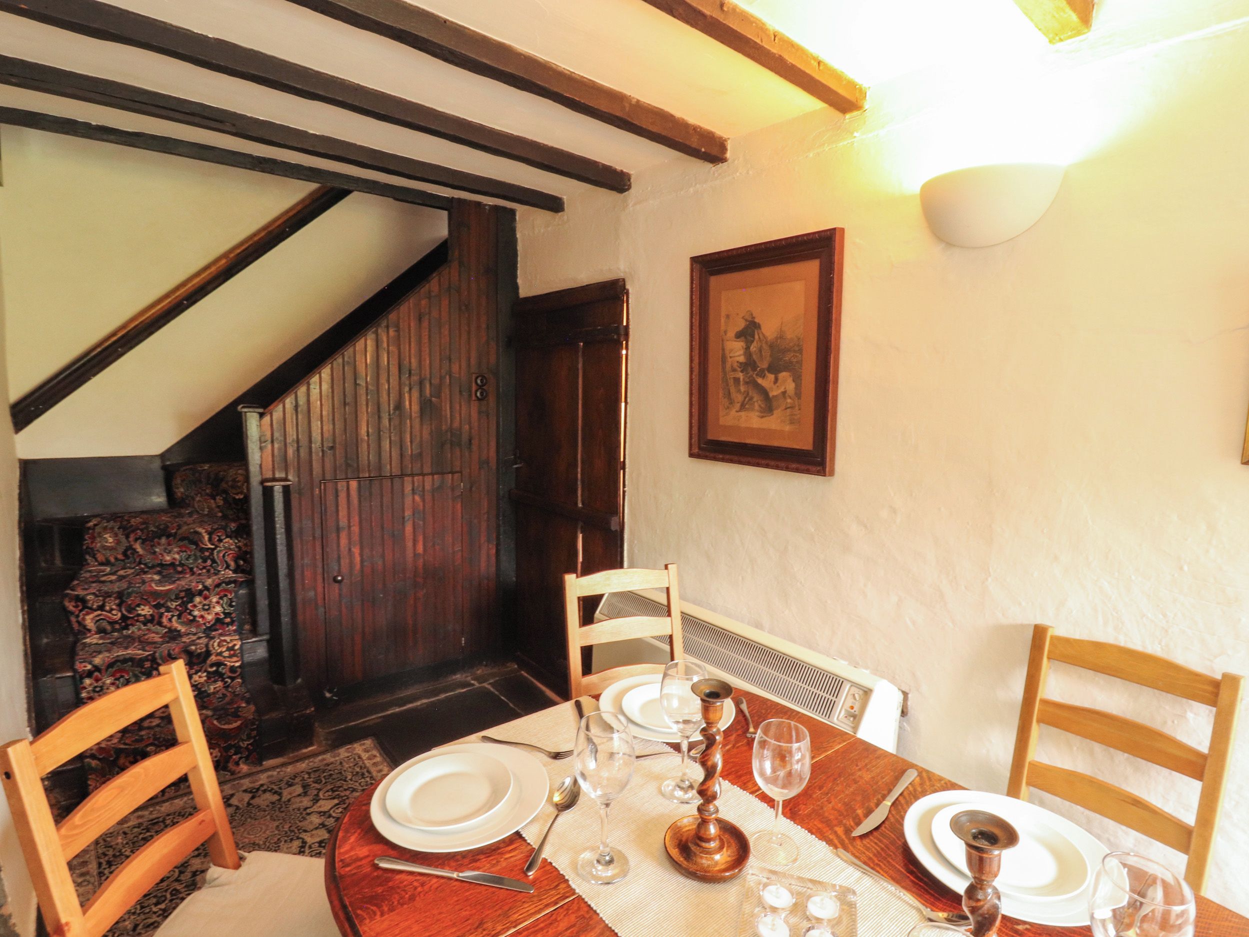 A dining area with a wooden table set for four, including plates, cutlery, and glasses.