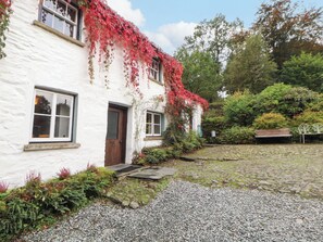 A white building with a cobblestone path leading to a wooden door.