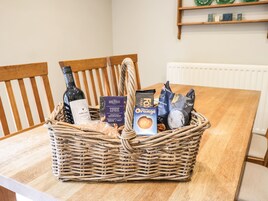 Una cesta de mimbre sobre una mesa de madera con diversos alimentos y una botella.