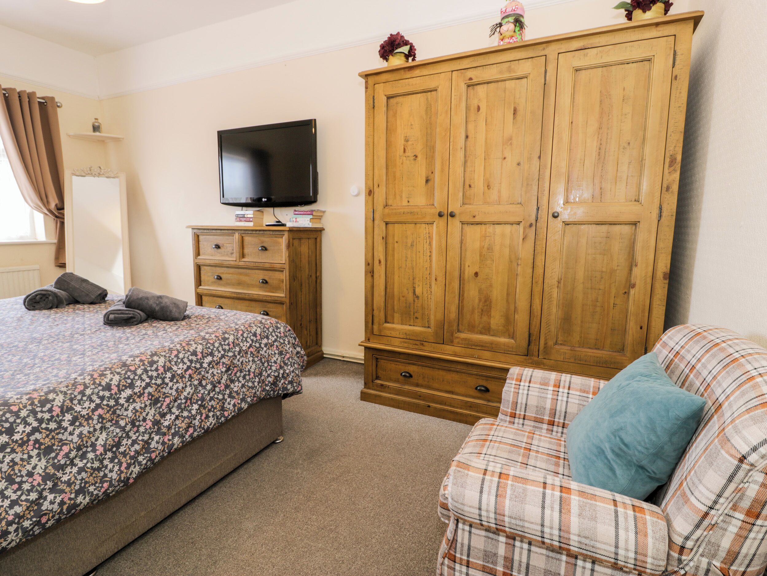 A bedroom with a bed, a wardrobe, a television, and a sofa.