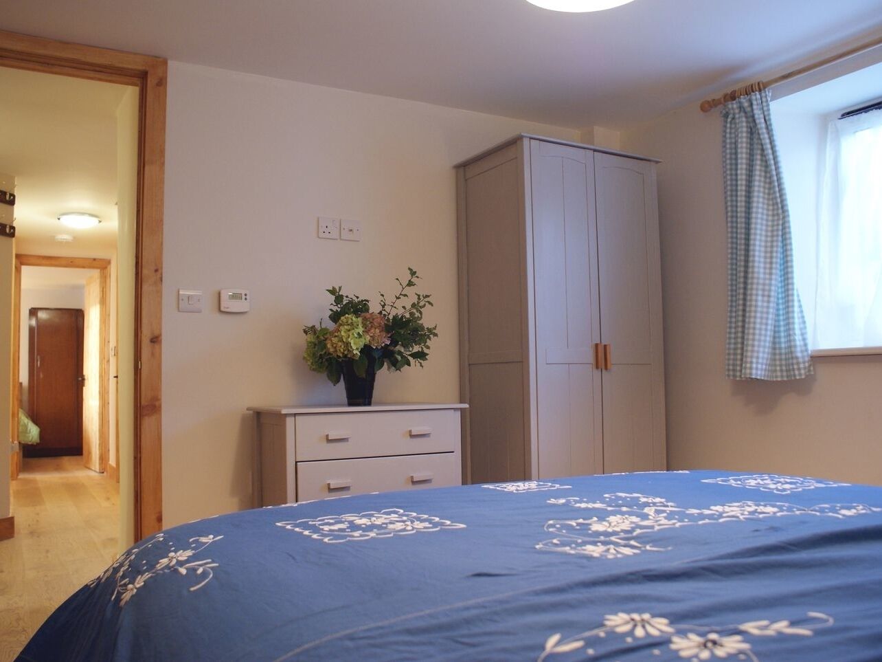 Een slaapkamer met een bed, een kledingkast, een kaptafel en een raam met gordijnen.