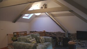 Un salón estilo loft con pared de piedra, chimenea, sofá y televisor.