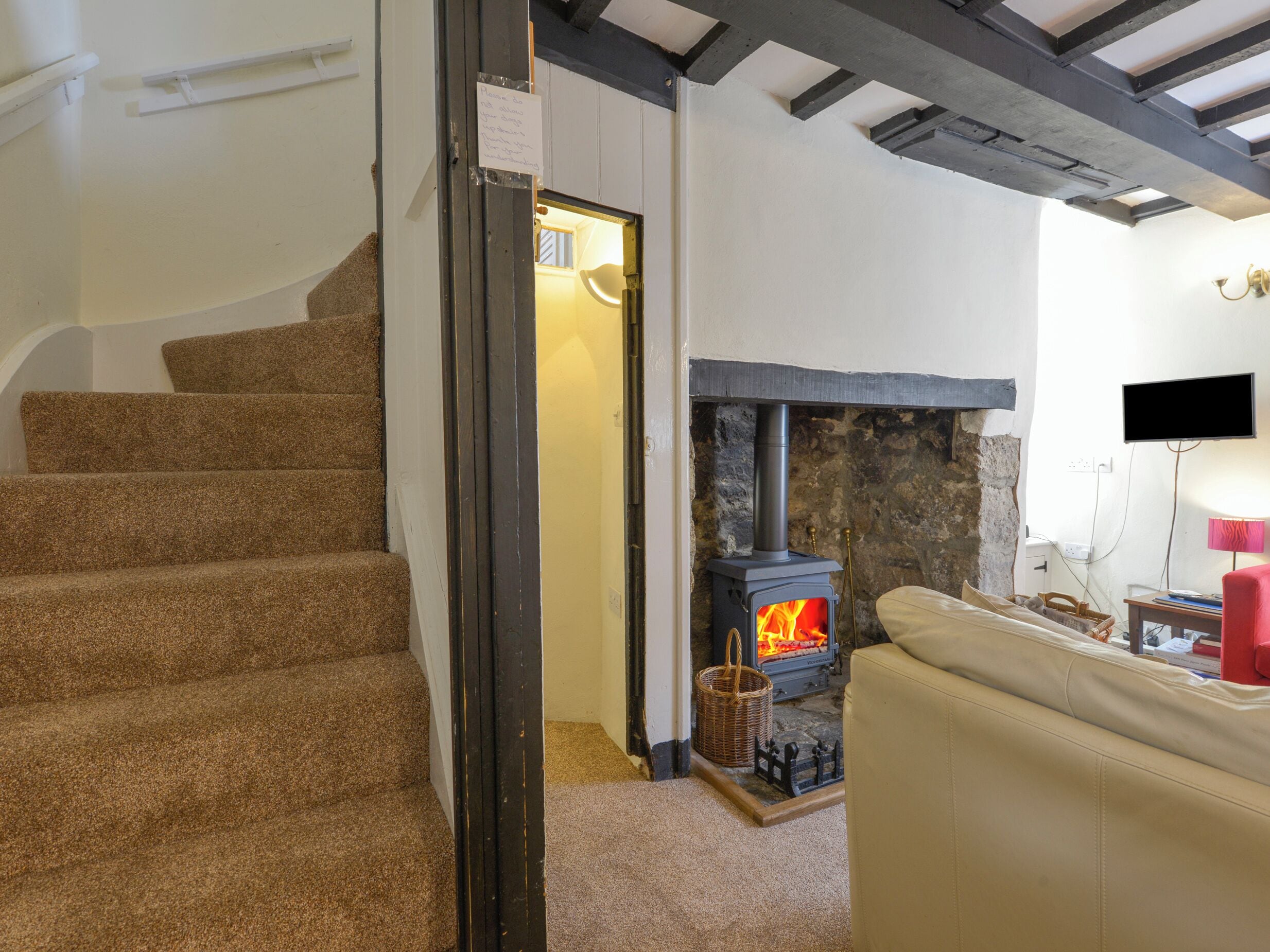 A staircase leading to a room with a stone fireplace, a television, and a red chair.