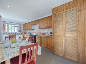 Una cocina con armarios de madera, una mesa de comedor con sillas y una puerta grande de madera.