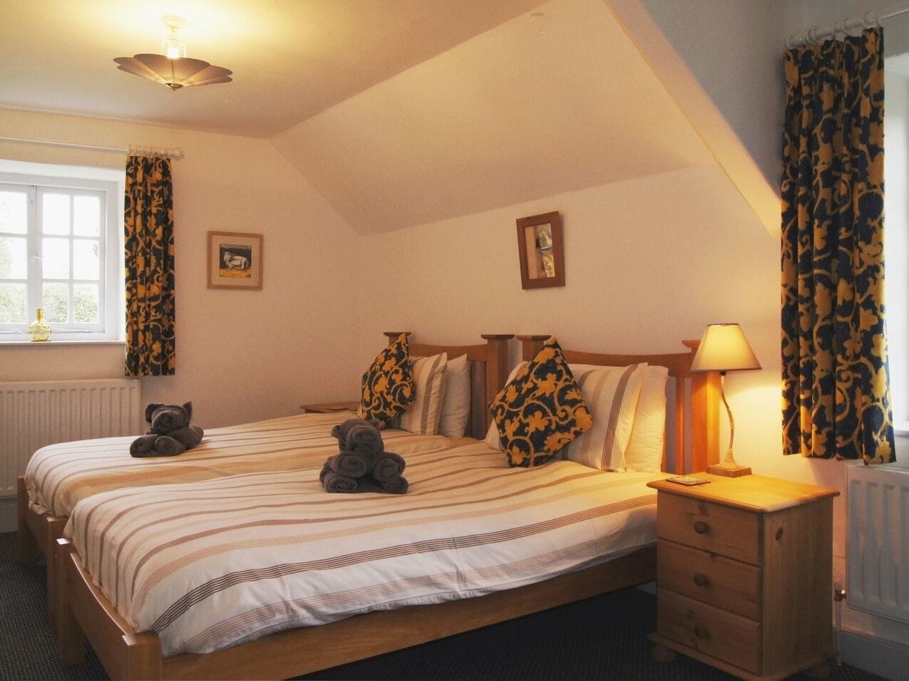 Quarto com cama, mesa de cabeceira, abajur e cortinas.