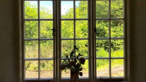 A large window with multiple panes, offering a view of a lush green landscape. - Heyden Cottage (Minehead)