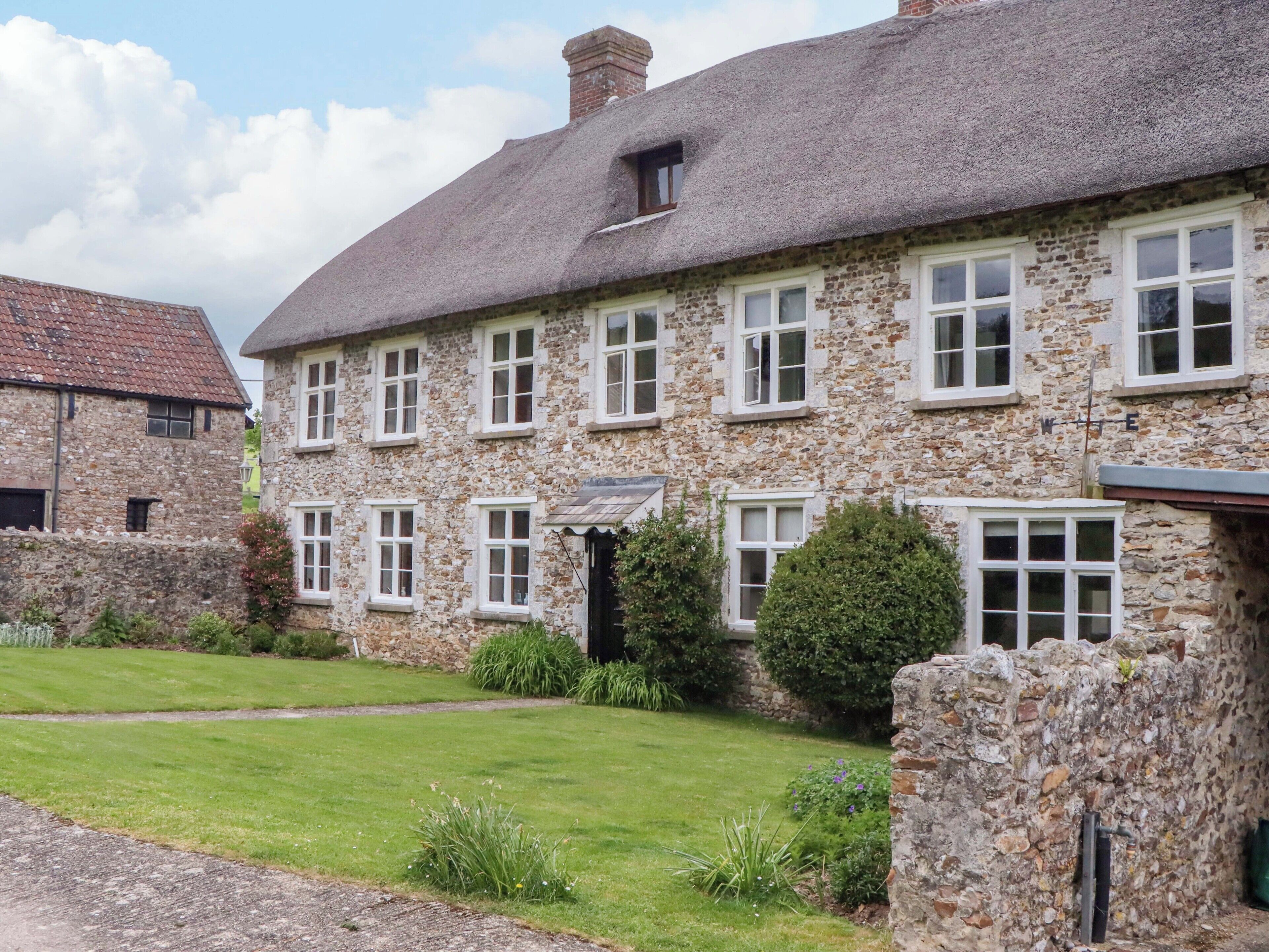 A stone building with multiple windows and a thatched roof.