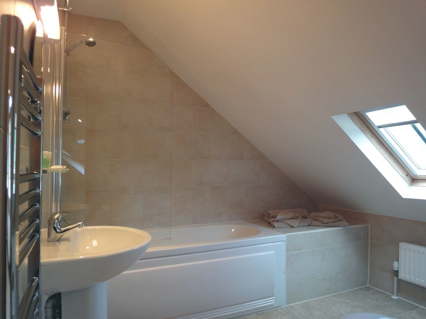 A modern bathroom with a freestanding bathtub, a built-in sink, and a skylight.