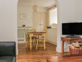 Ein Essbereich mit Holztisch und -stühlen, einem Fernseher auf einem Holzschrank und einem Korbwannenkorb.