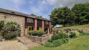 A stone house with a garden, a stone wall, and a grassy lawn.