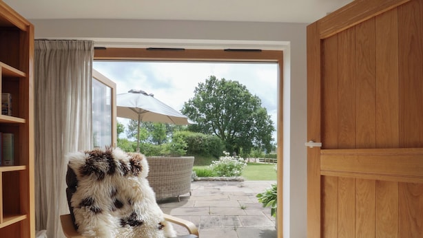 A cozy room with a wooden chair, a bookshelf, and a sliding glass door leading to a garden.