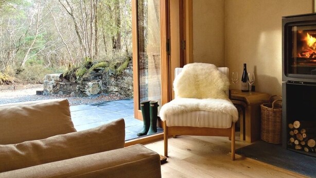 A cozy room with a fireplace, a chair, and a view of the outdoors.