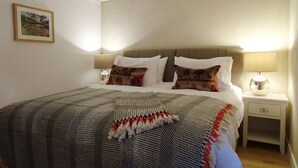 A neatly made bed with patterned bedding, two bedside tables with lamps, and a framed picture on the wall.