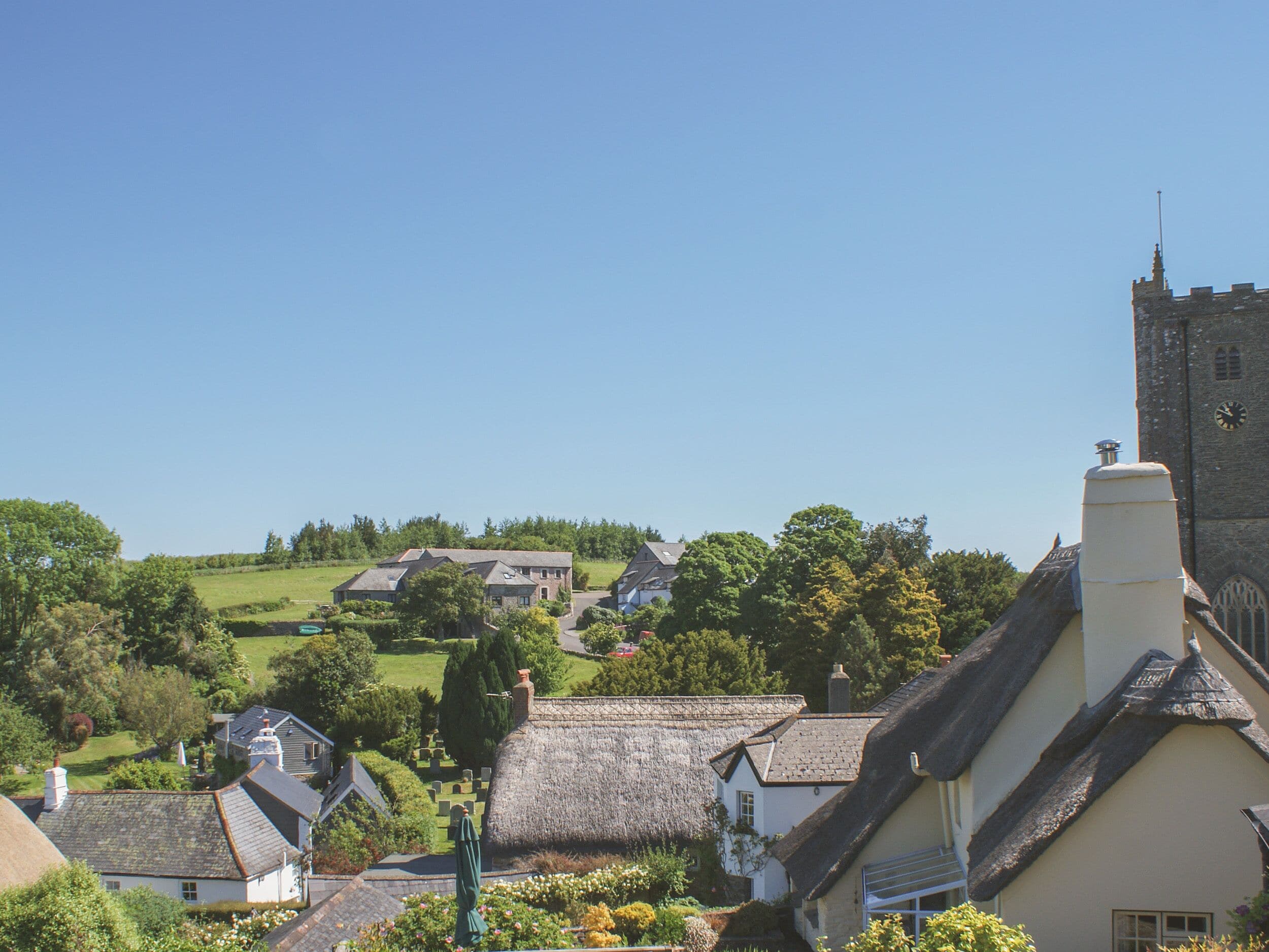 A village with traditional thatched-roof houses, a church, and a prominent tower.