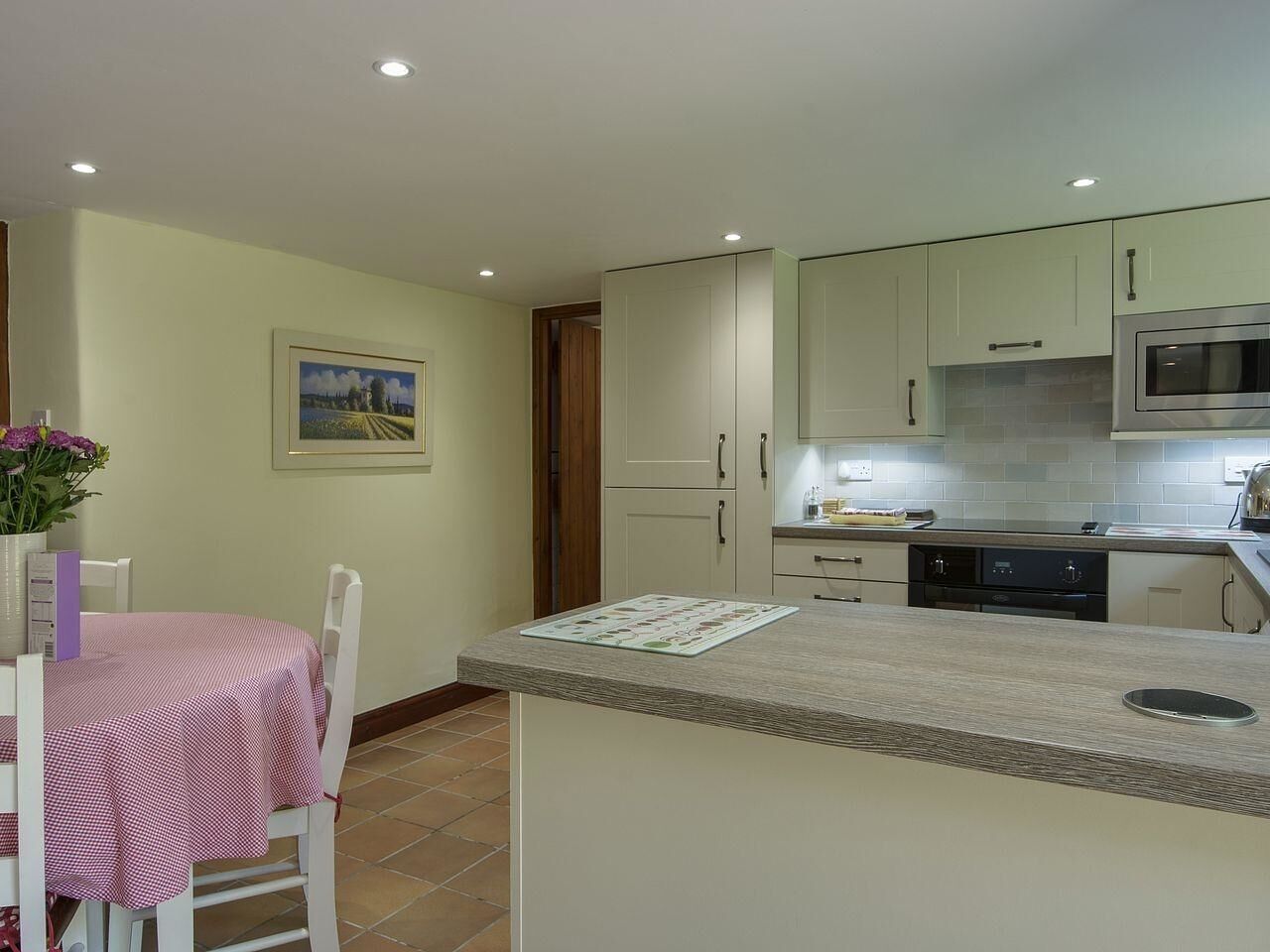A compact kitchen with a dining area, featuring a small island, cabinets, and a microwave.