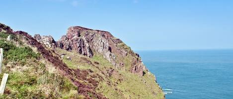 A coastal cliff with a path leading to a viewpoint overlooking the sea.