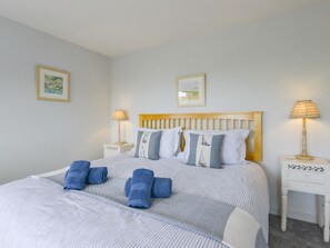 A neatly made bed with blue towels, a wooden headboard, and two bedside tables with lamps.