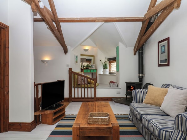 A cozy living room with a television, a wooden coffee table, a striped sofa, and a fireplace.