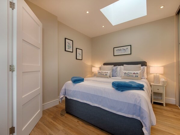 A bedroom with a bed, bedside tables, and a skylight. - Junket Studio (Plymouth)