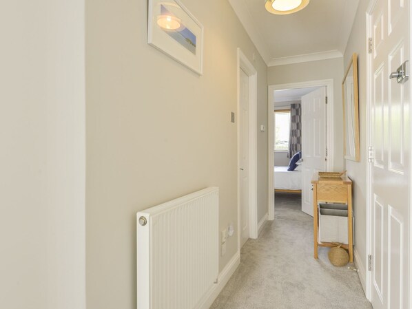 A hallway with a radiator, a framed picture on the wall, and a door leading to a bedroom. - 3 Tarifa (Kingsbridge)