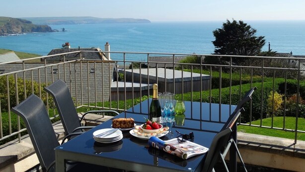 A table with a bottle, glasses, and food, overlooking a coastal view. - 3 Tarifa (Kingsbridge)