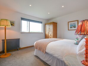 Un dormitorio con cama, radiador, ventana, armario de madera y lámpara.
