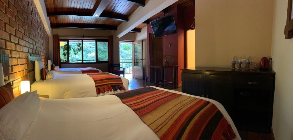 A hotel room with two beds, a television, and a view of the outdoors.